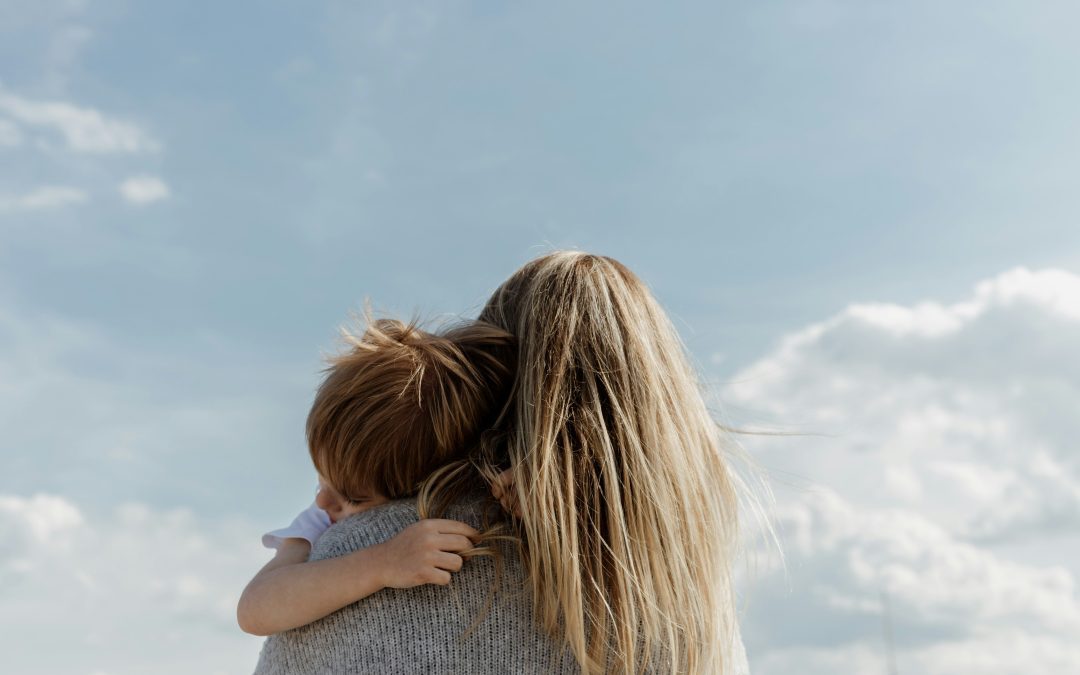 Woman who has parental responsibility holds her young son whilst outdoors.