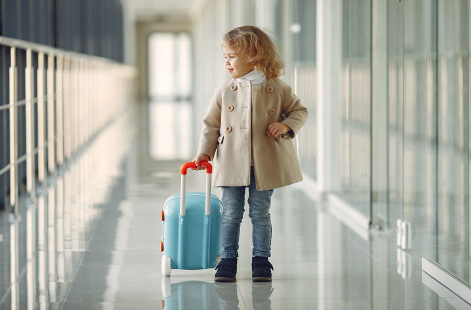 Little girl with suitcase in an airport going on holiday