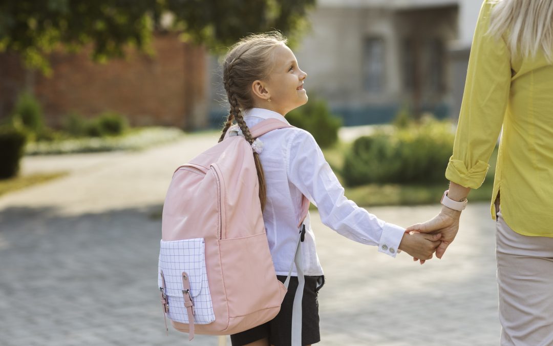 young child holds her mother's hand whilst on the way to school after parents are divorced